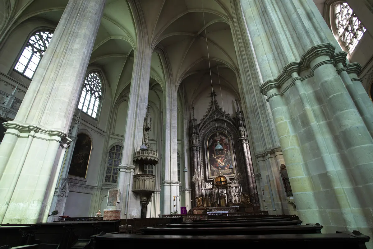 The nave of the Minoritenkirche with tall pale-green piers rising into ribbed vaults and the neo-Gothic high altar at the far end.
